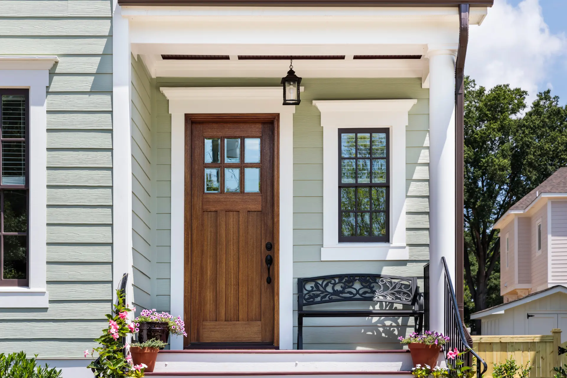 Pale green siding with a wood entry door and black-framed window