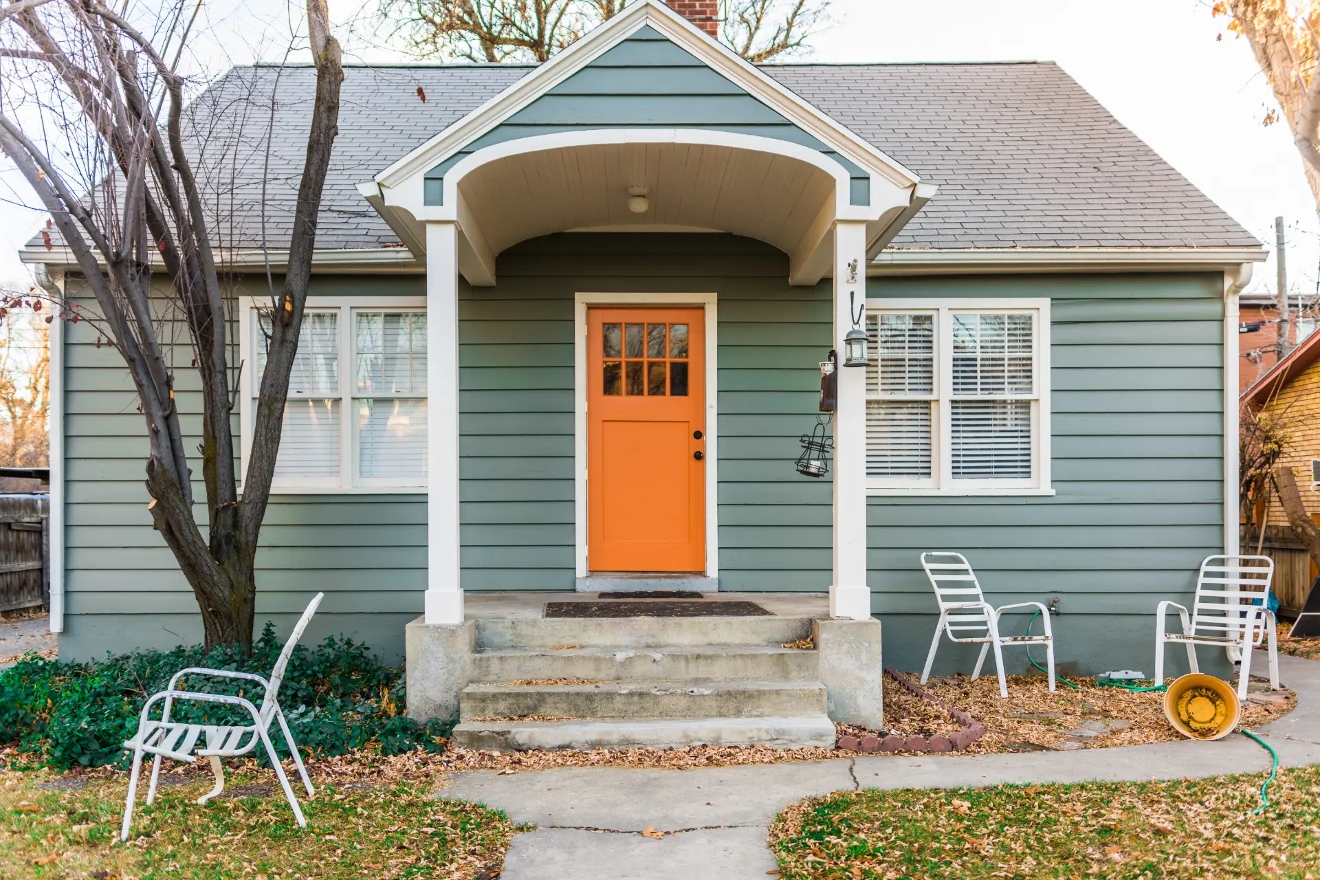 Green home exterior with white-trimmed windows and a covered entry